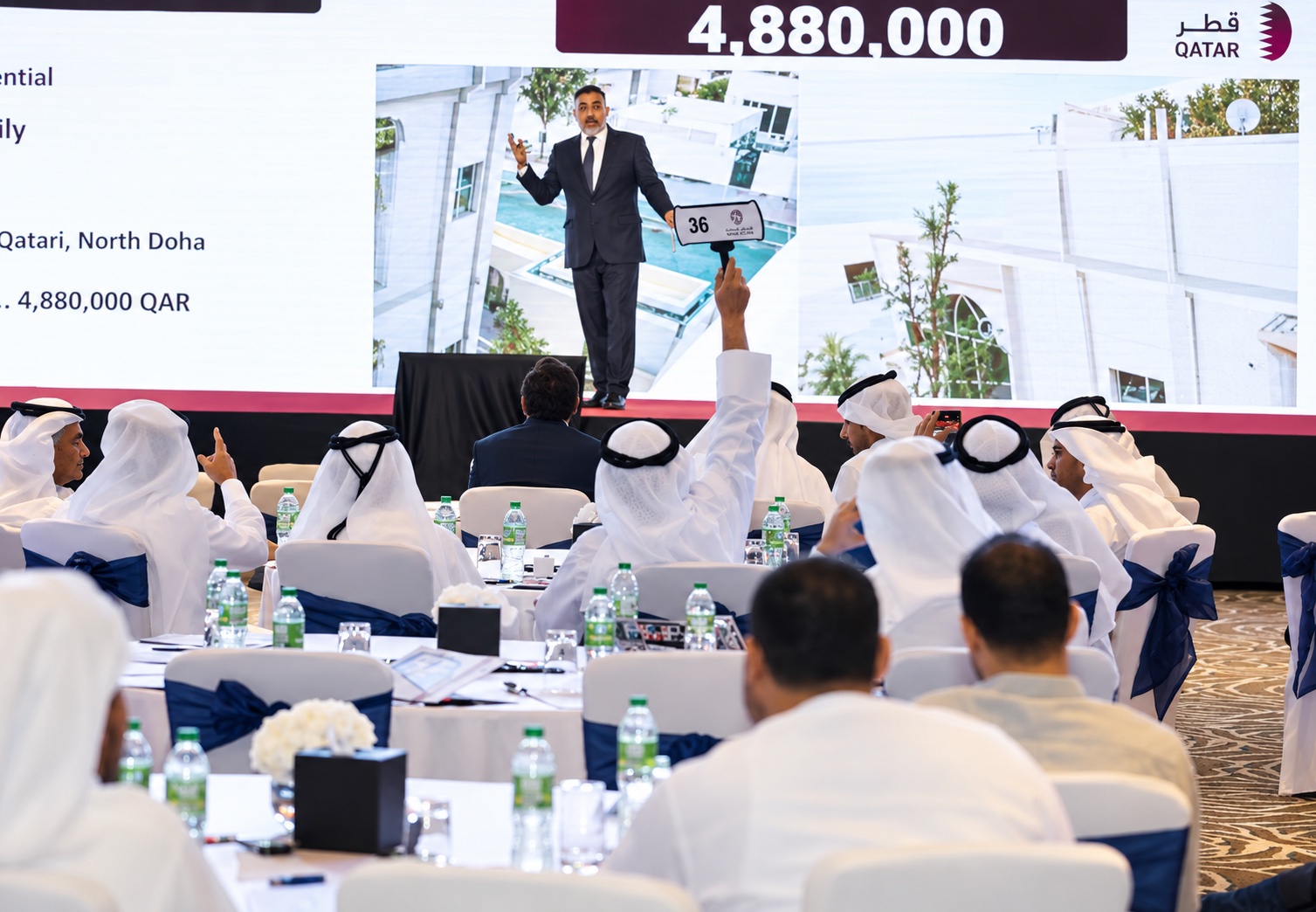 Live auction hall with bidders and an auctioneer on stage